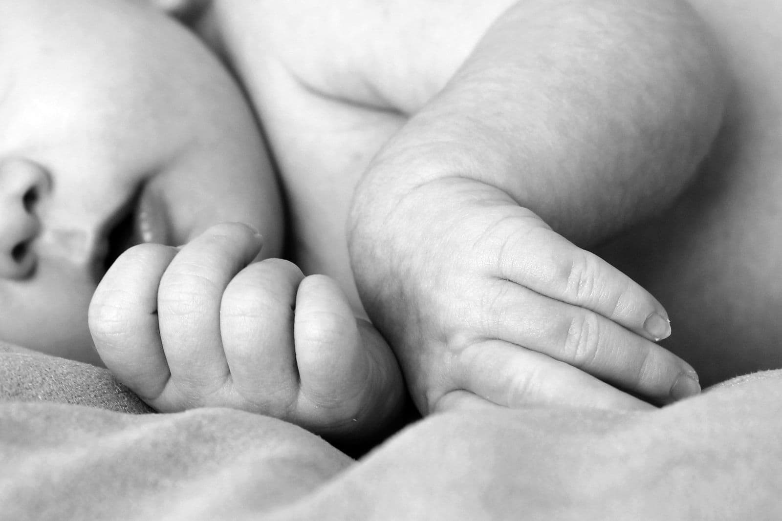A tiny newborn hand resting in a parent's hand