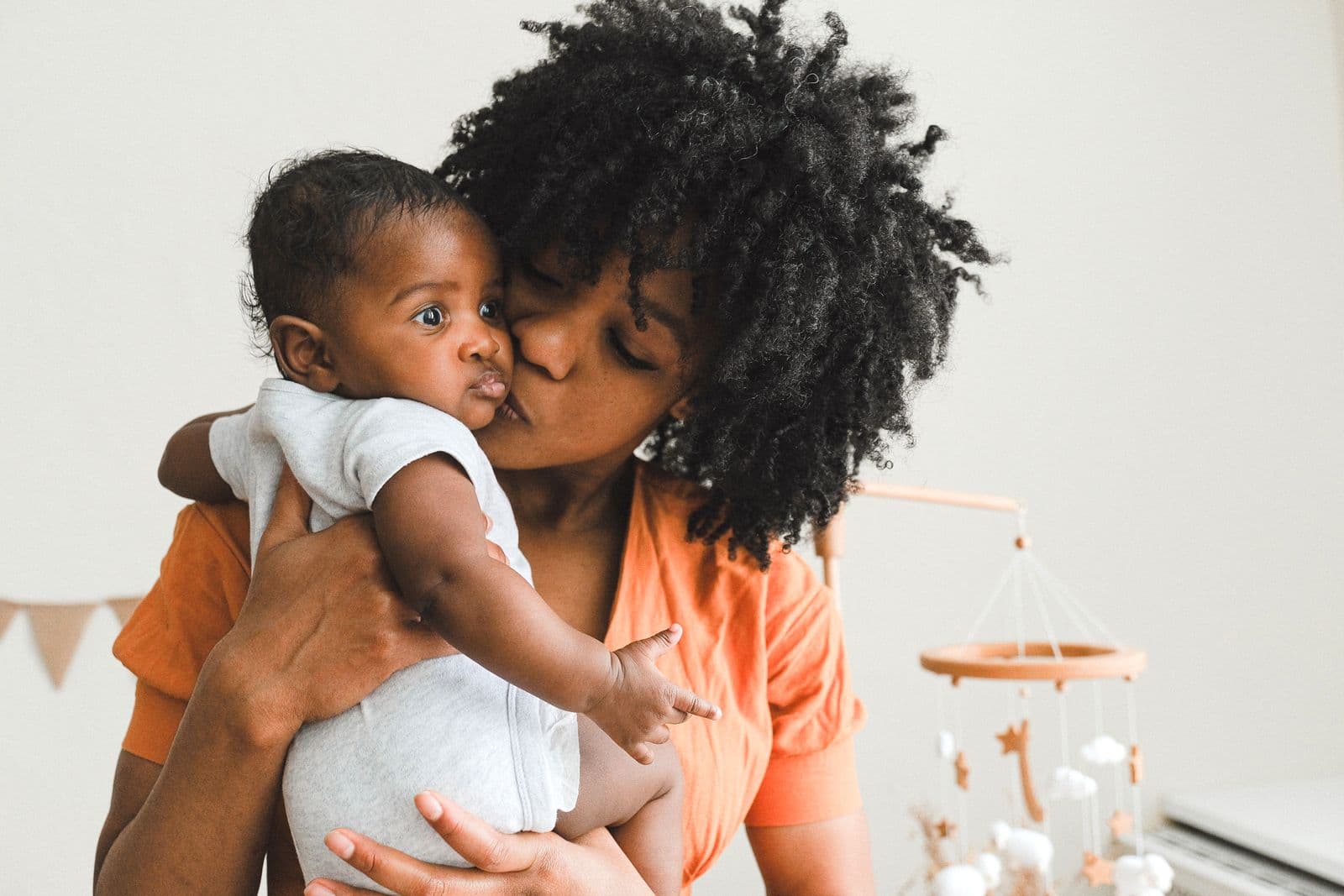 A mother kissing her baby's cheek in warm light