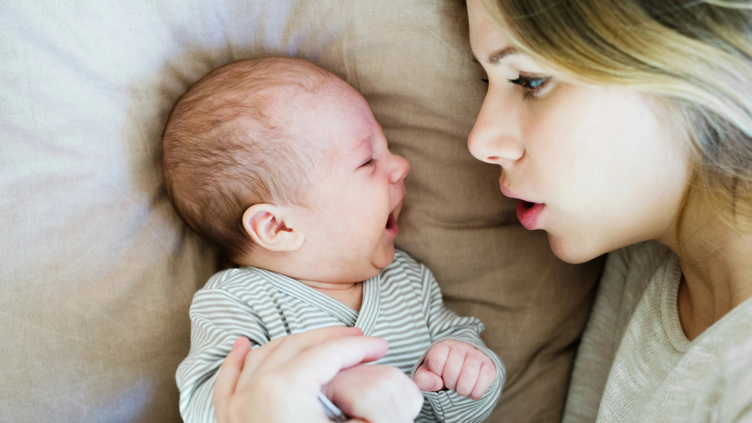 A mother gently holding her baby, looking down with a tender, worried expression