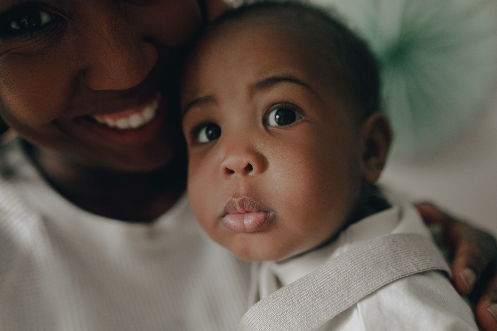 A smiling mother resting cheek to cheek with her baby