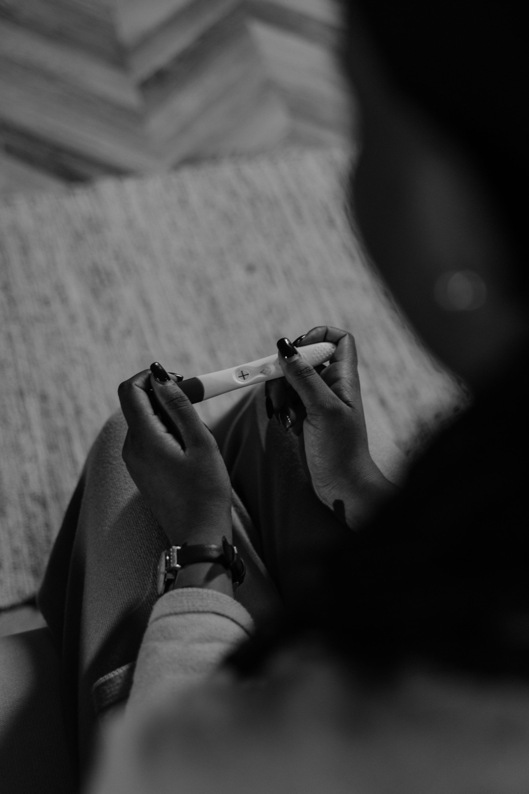 A woman's hands holding a pregnancy test, photographed in low light