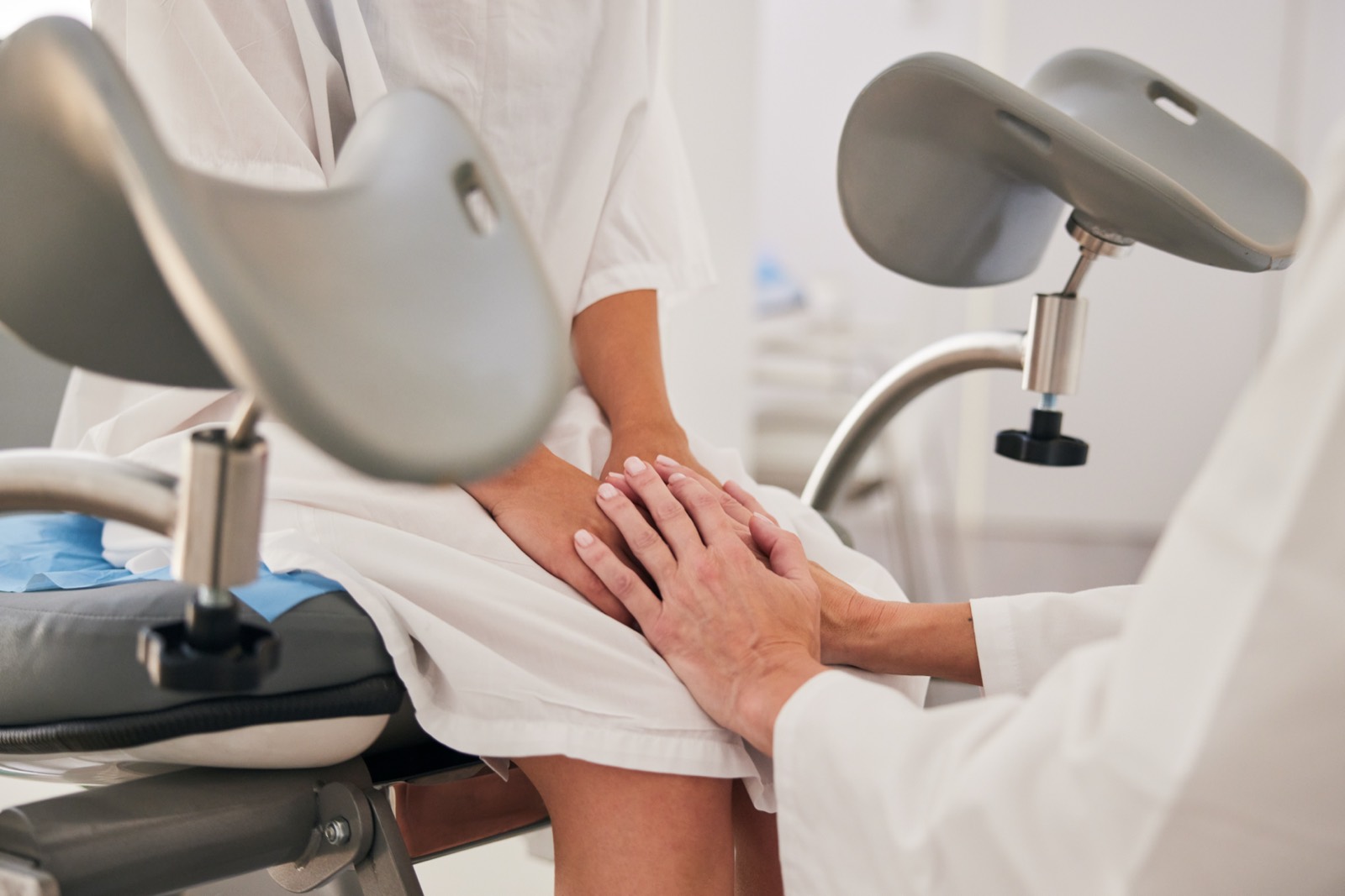 A clinician resting a reassuring hand on a patient during a fertility exam